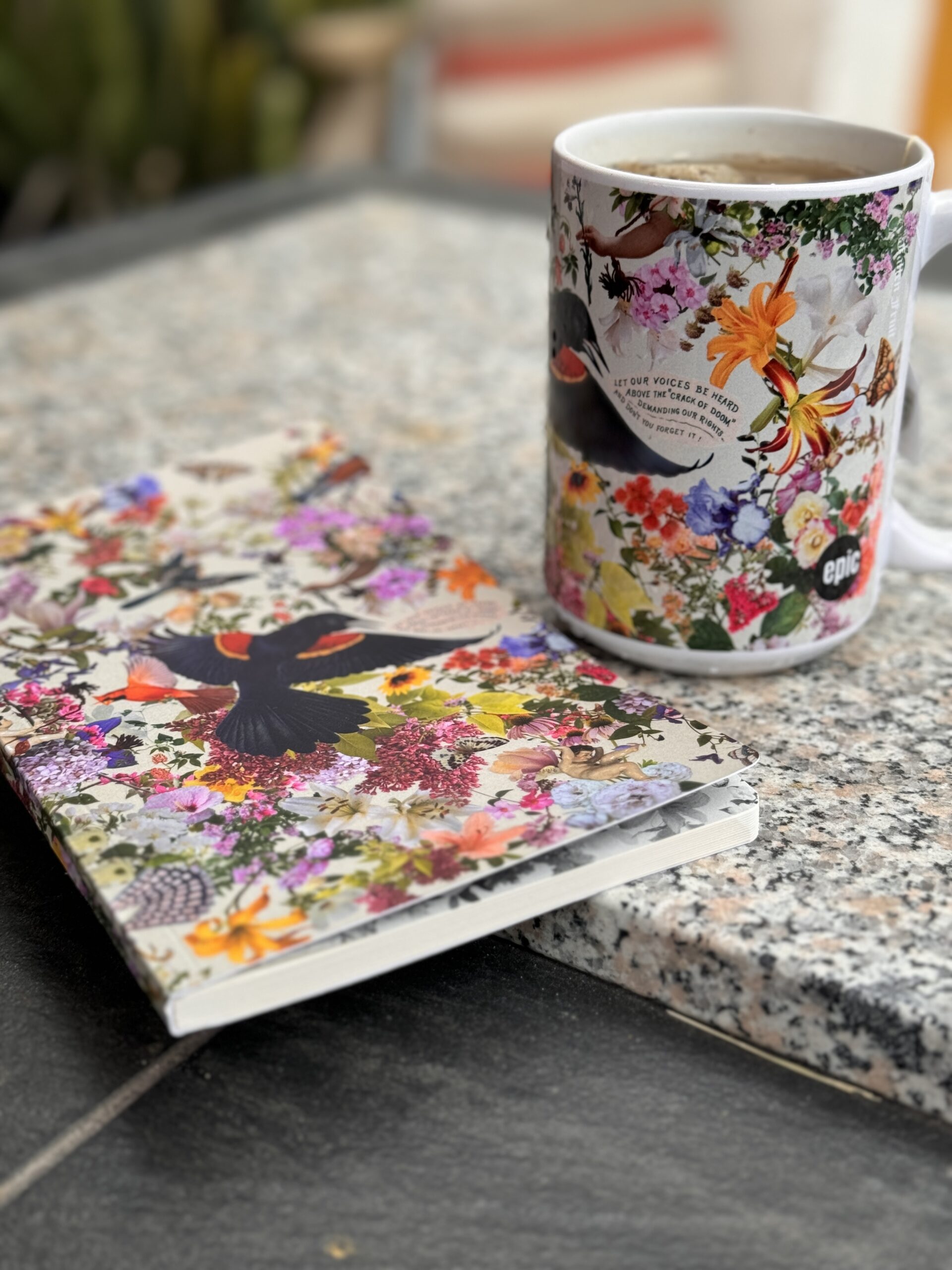 Photo of a mug and notebook printed with birds, flowers, and plants.