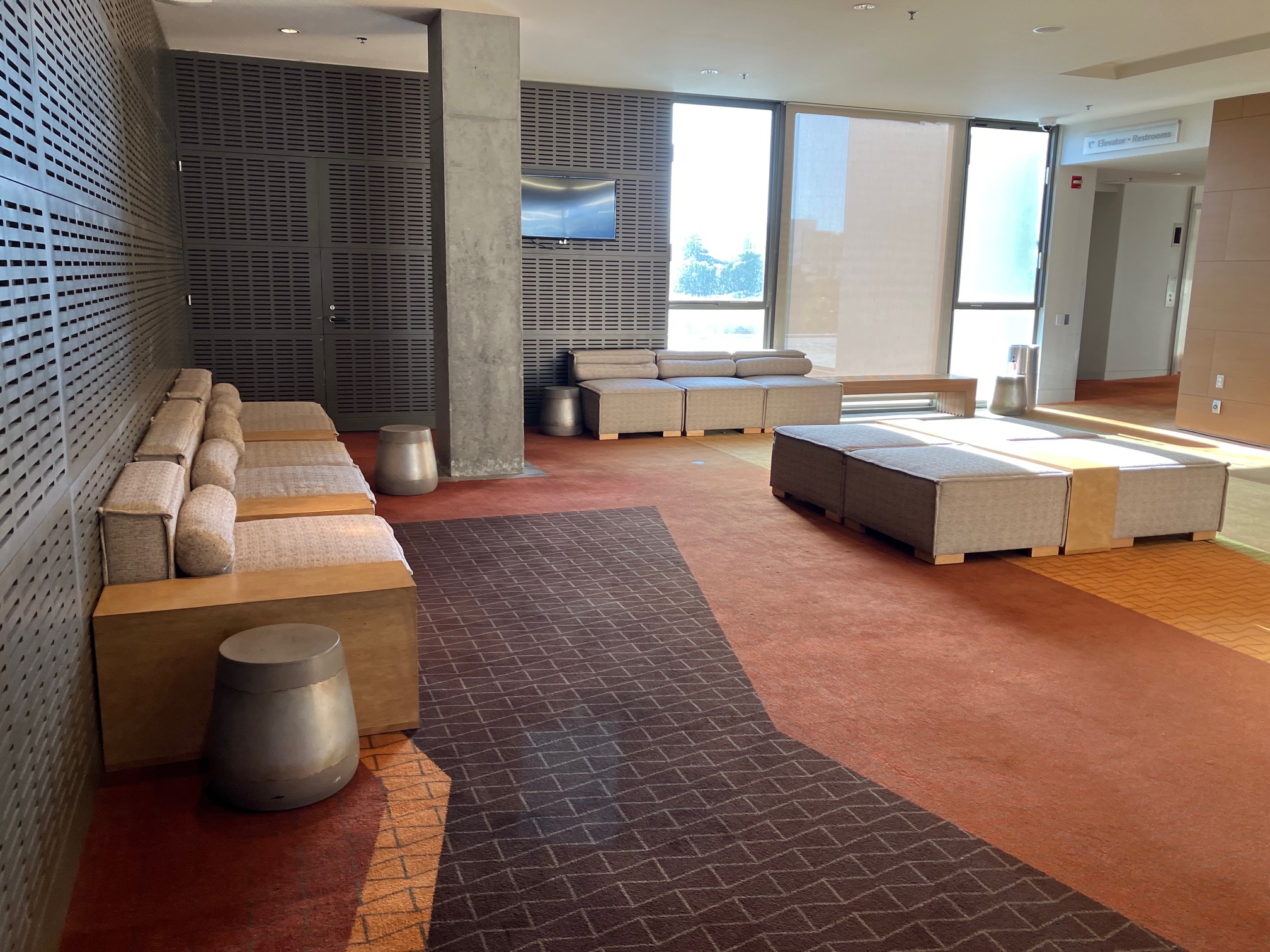 The central seating area of the Broad Stage lobby is an open space with benches on the edges and tall tables in the middle.